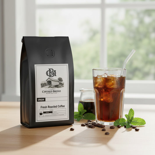 Coffee bag beside iced coffee glass with mint and coffee beans