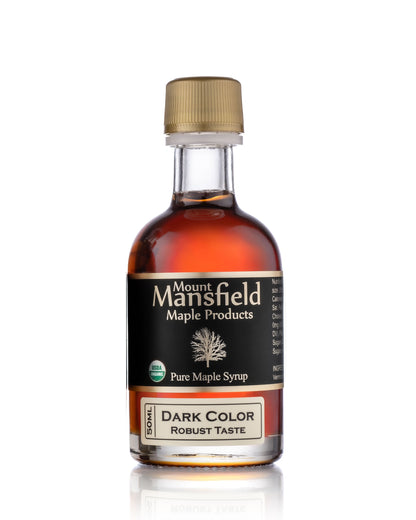 Dark color maple syrup in glass bottle, tan cap, dark syrup and black label