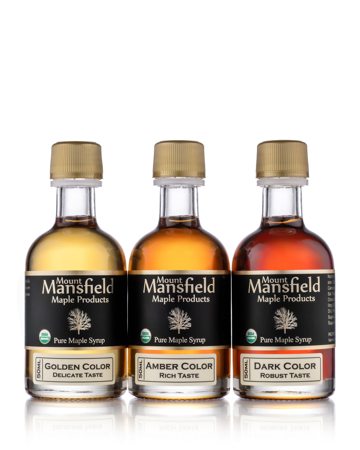 Three mini maple syrup bottles with gold caps: golden, amber, and dark labels