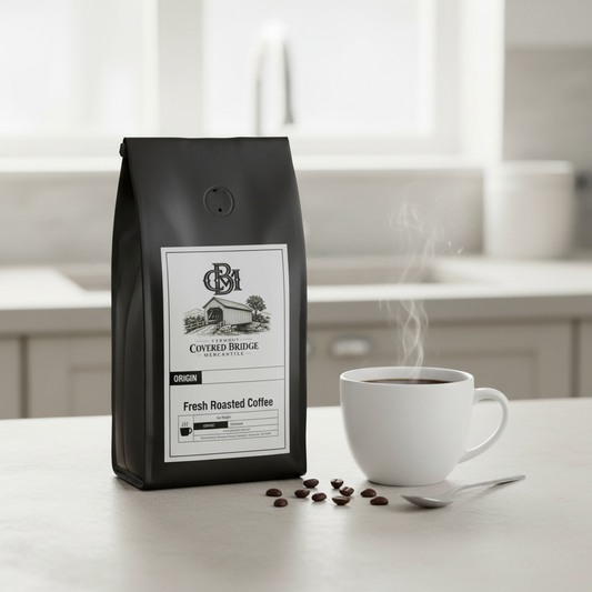 Black coffee bag with label beside white cup of coffee and scattered beans